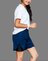 A young female model wearing a black V-neck activewear tee and blue shorts.